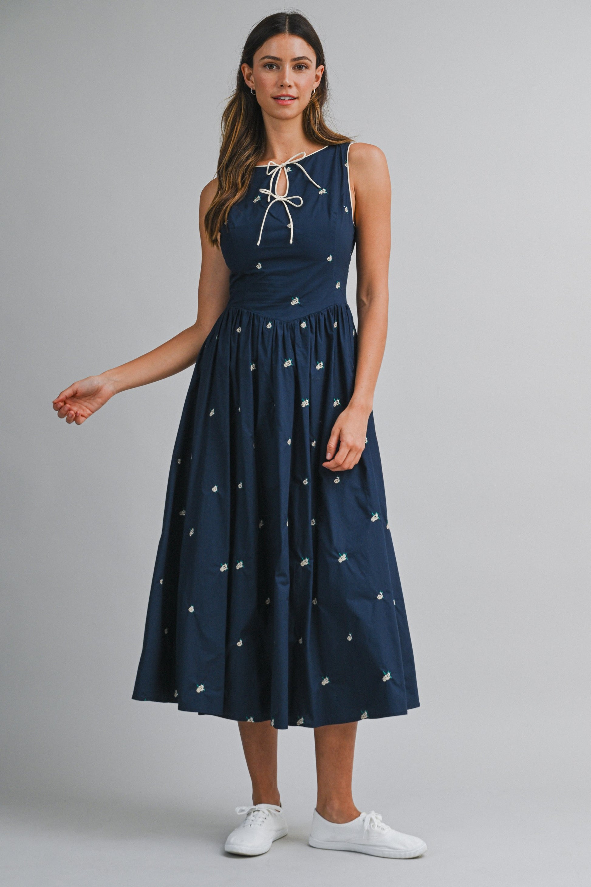 A navy sleeveless midi dress with floral embroidery, a keyhole self-tie neckline, fitted bodice, smocked back, and softly gathered A-line skirt.