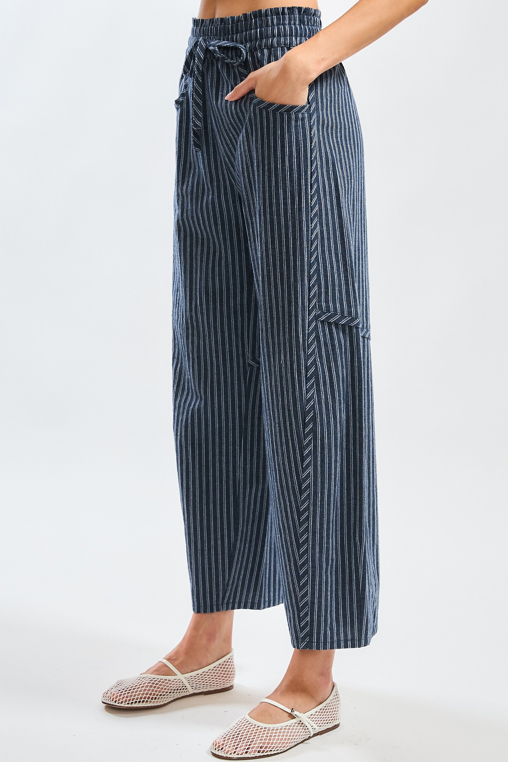 A pair of women's high-waisted wide-leg cropped pants featuring a indigo and white vertical pinstripe pattern with a gathered elastic drawstring waistband and front pockets.