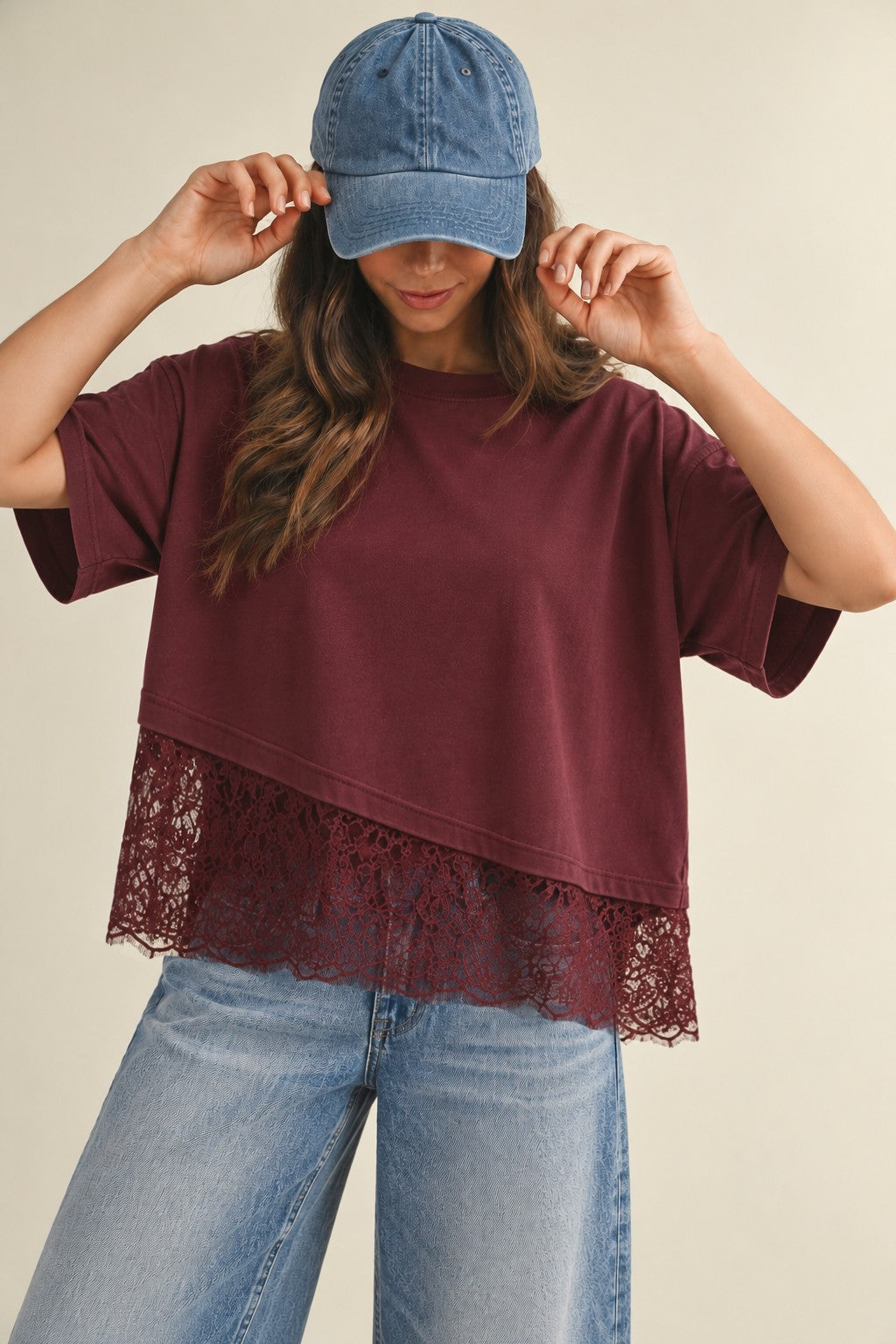 A women's relaxed short-sleeve burgundy crewneck T-shirt featuring dropped shoulders and an asymmetrical hem trimmed with sheer floral lace.