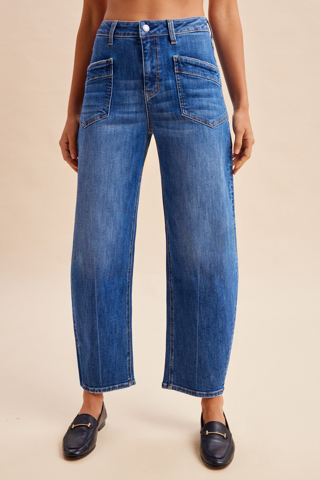 Stretch denim slim barrel leg jeans in dark wash denim featuring a high-rise waist, angled front utility patch pockets, and distinct center seam detailing down each leg.