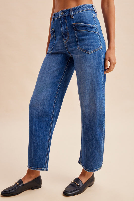 Stretch denim slim barrel leg jeans in dark wash denim featuring a high-rise waist, angled front utility patch pockets, and distinct center seam detailing down each leg.