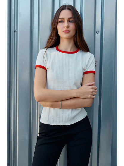 A women's ivory pointelle knit crewneck ringer t-shirt featuring bright red contrast trim along the neckline and sleeves, short sleeves, and a textured vertical diamond stitch pattern.