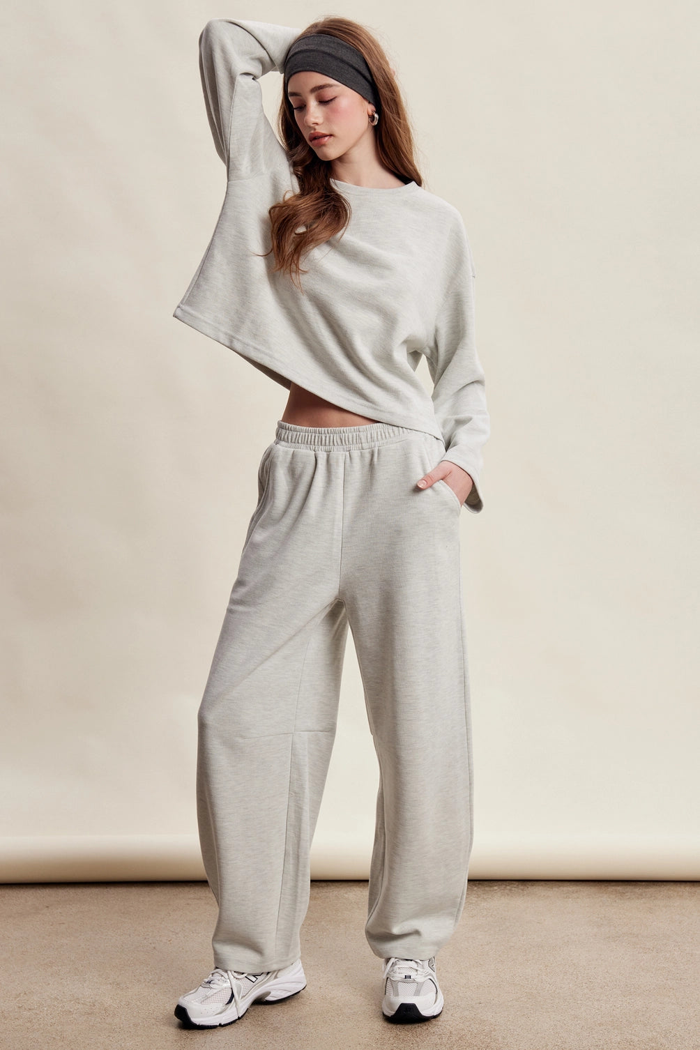 A women's heather gray two-piece stretch cotton lounge set featuring a long-sleeve crewneck top and matching high-waisted relaxed wide-leg pants.