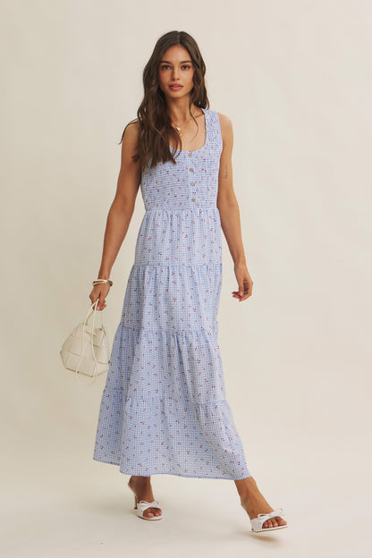 Cherry gingham print maxi dress in the color sky blue. The dress has a smocked bust, round neck, button-down detail, side pockets and comes lined. 
