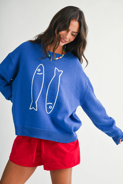 A women's royal blue long-sleeve knit crewneck sweater featuring a white embroidered sardine graphic on the front and ribbed trim along the collar, cuffs, and hem.