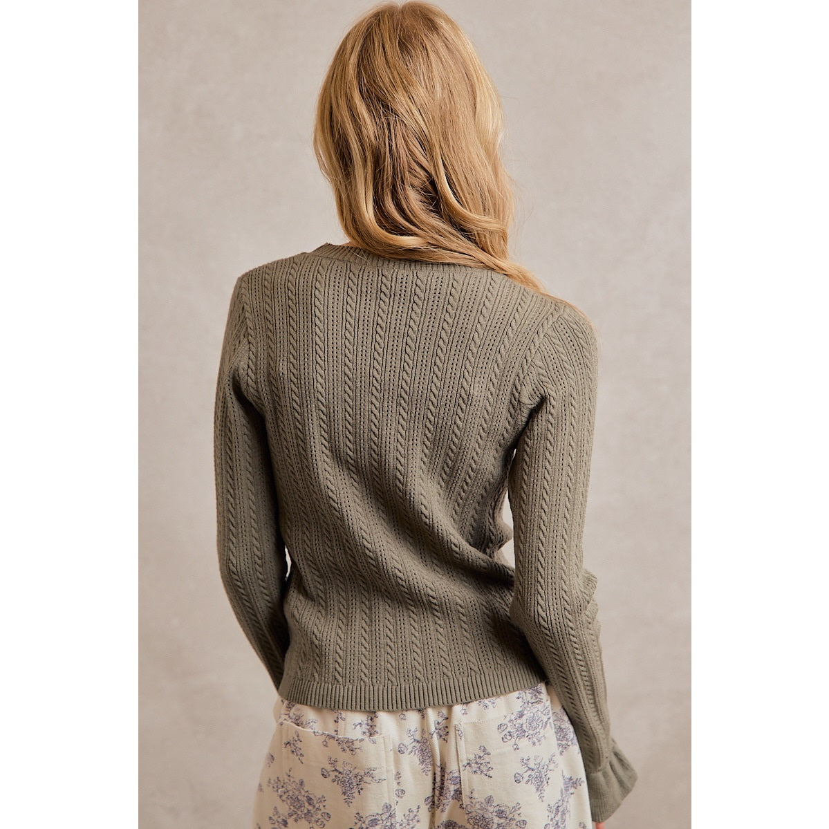 A women's olive green long-sleeve cable-knit sweater featuring a mock neckline, ribbed hem, and ruffled flare knit cuffs.
