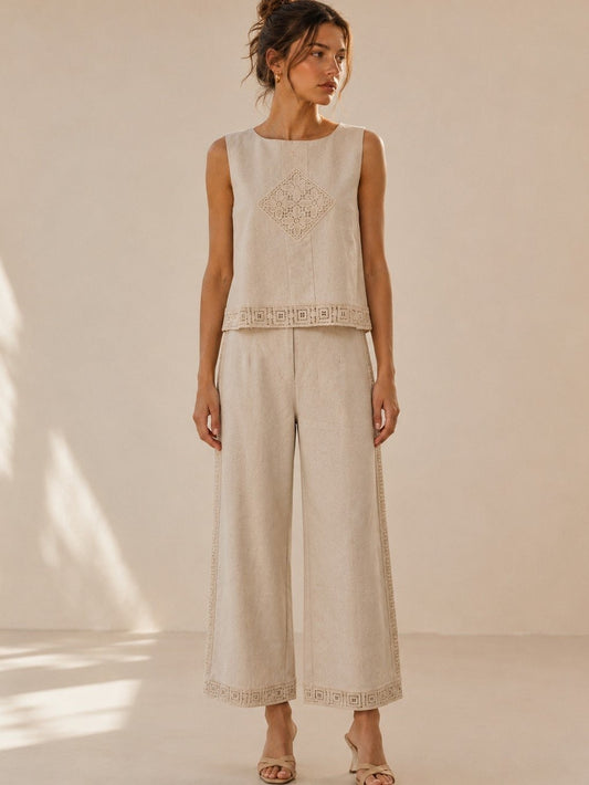 A women's two-piece linen-blend clothing set in an oat color featuring a sleeveless top with a chest diamond crochet applique and matching high-waisted wide-leg pants with lace trim panels along the sides and hems.