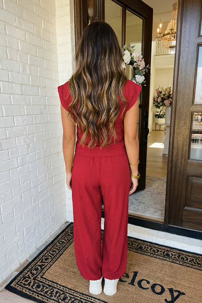 A women's two-piece lounge set in crimson red featuring a sleeveless top with a tulip crossover front hemline and matching high-waisted wide-leg pants.
