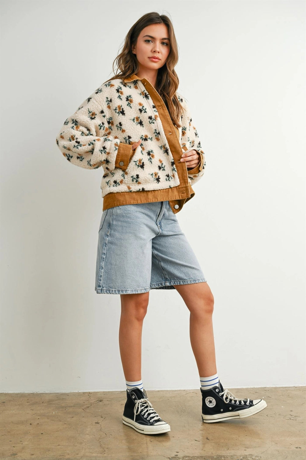 A women's cream floral printed plush sherpa fleece jacket featuring camel brown twill contrast trim, front button closures, and side pockets.