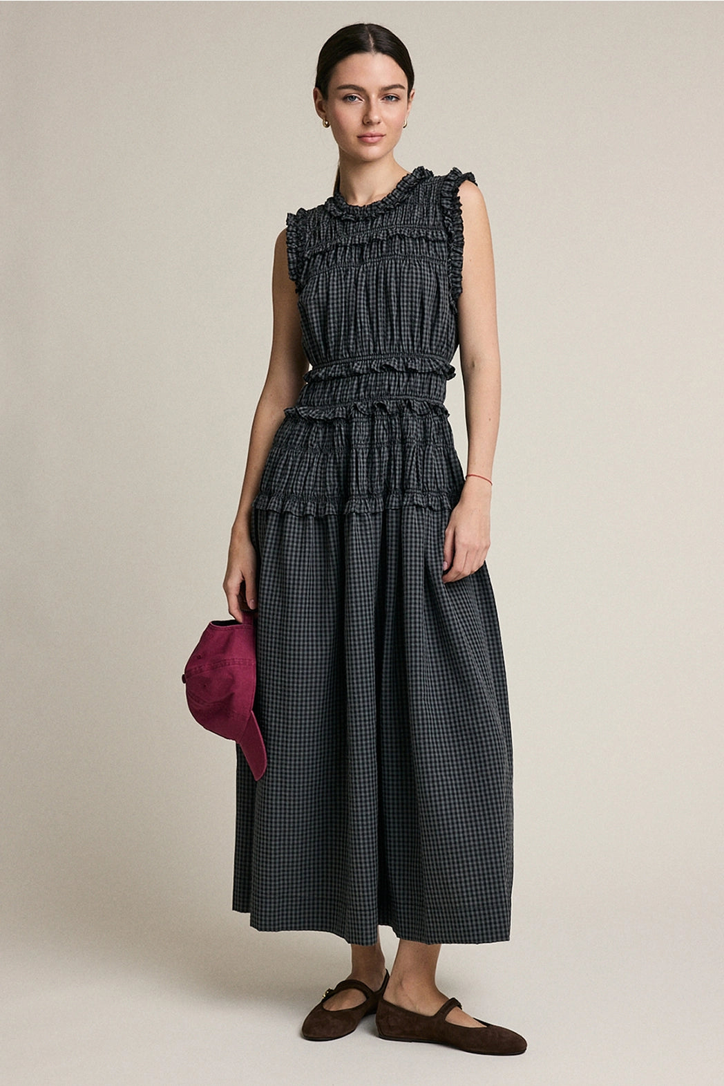 A women's sleeveless maxi dress in a dark gray and black plaid pattern featuring a high ruffled neckline, a fully elasticized smocked bodice, and a flowing tiered skirt with delicate ruffle trim.