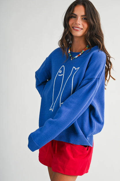 A women's royal blue long-sleeve knit crewneck sweater featuring a white embroidered sardine graphic on the front and ribbed trim along the collar, cuffs, and hem.