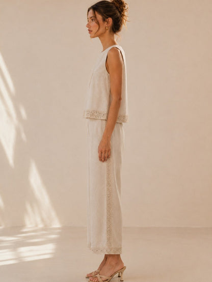 A women's two-piece linen-blend clothing set in an oat color featuring a sleeveless top with a chest diamond crochet applique and matching high-waisted wide-leg pants with lace trim panels along the sides and hems.