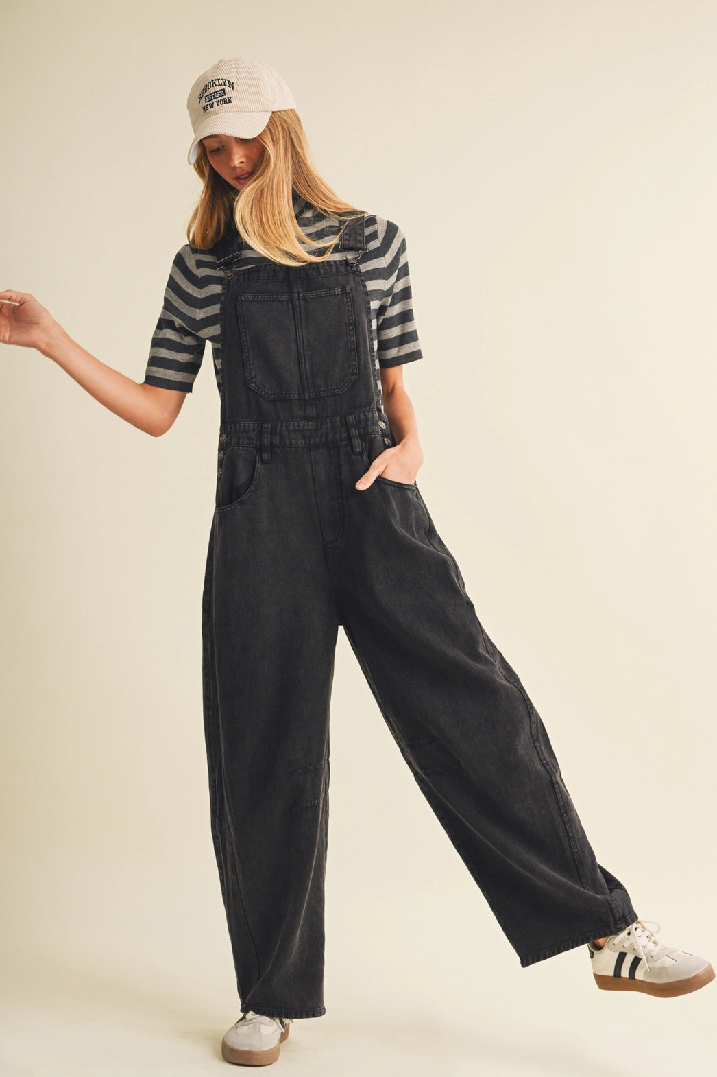A pair of women's high-waisted wide-leg twill overalls in a vintage washed black denim finish featuring classic adjustable shoulder straps, a front chest pocket, and side pockets.