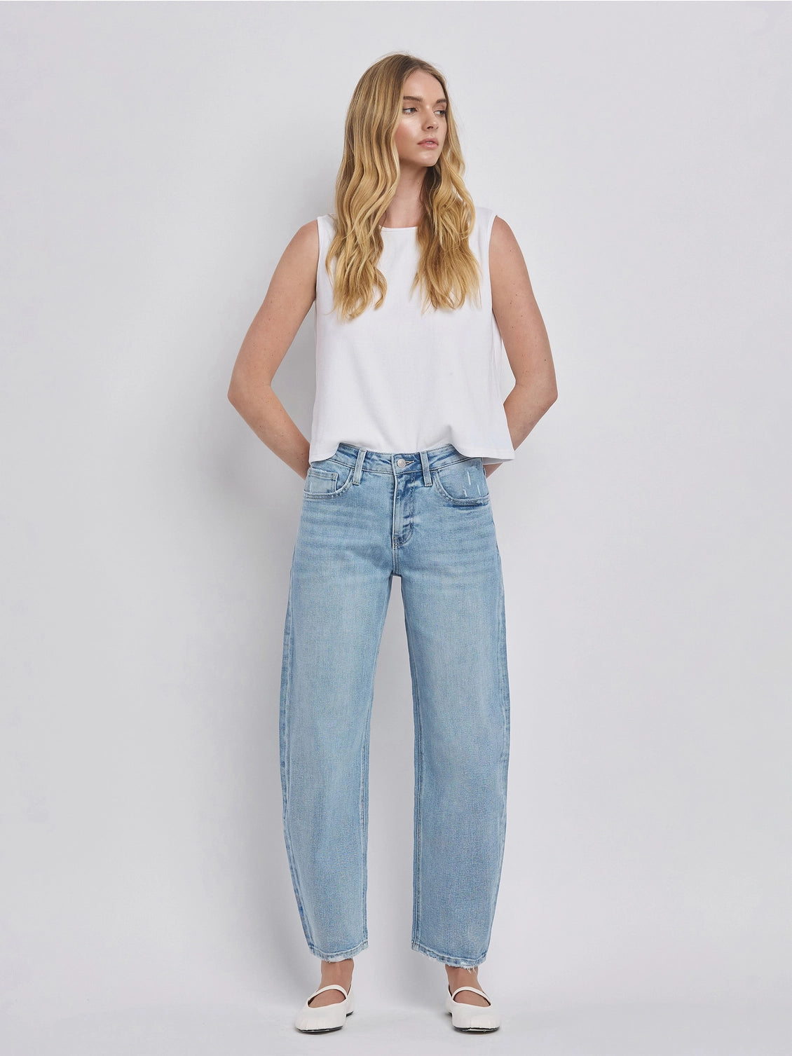Women's light wash high-rise barrel leg jeans featuring a relaxed curved silhouette, subtle distressing, and an ankle-length hem.