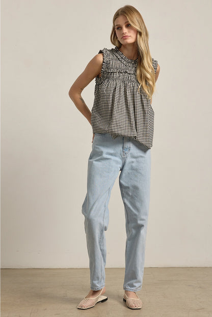 A women's sleeveless black and white gingham check blouse featuring a smocked high mock neckline, ruffle shoulder details, and a relaxed baby-doll silhouette.