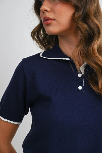 A women's navy blue short-sleeve fine-knit polo top featuring white scalloped contrast trim on the collar, button placket, and sleeve cuffs.