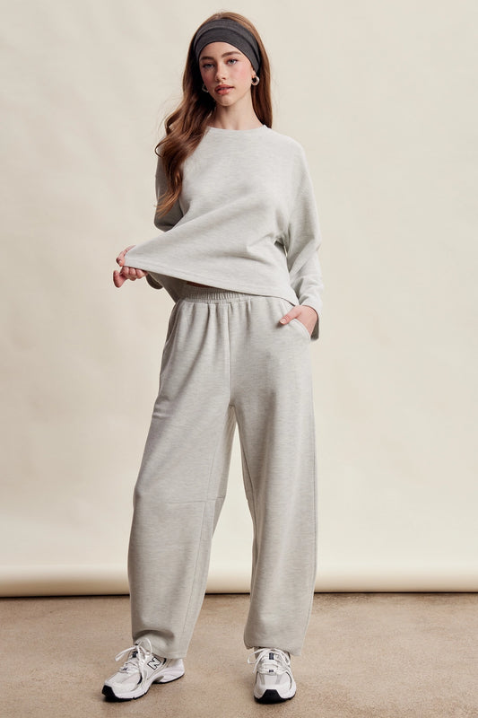 A women's heather gray two-piece stretch cotton lounge set featuring a long-sleeve crewneck top and matching high-waisted relaxed wide-leg pants.