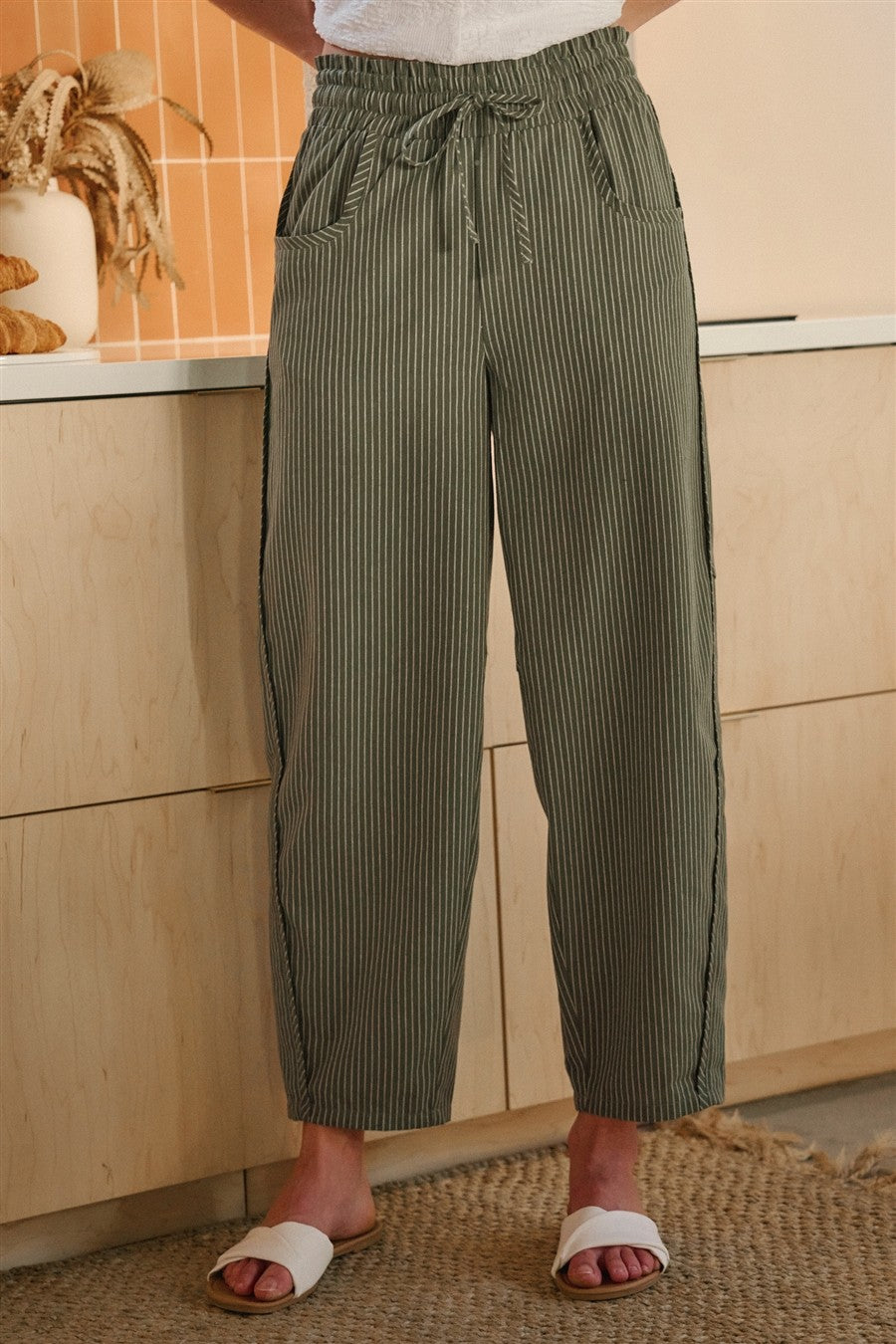 Olive and oatmeal vertical striped linen-blend pants featuring a high-rise elastic drawstring waistband, a relaxed tapered leg, and functional side utility pockets.