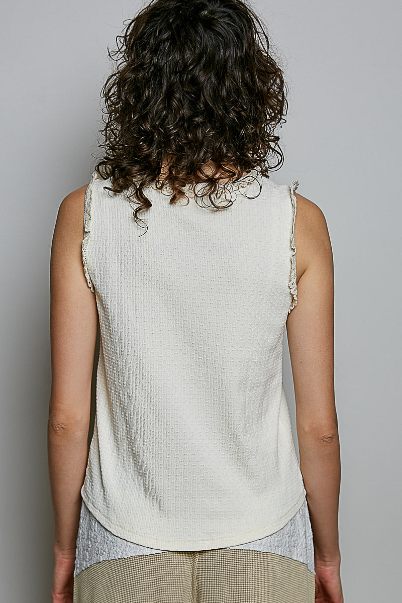 A women's sleeveless cream textured waffle-knit top featuring a button-front closure and delicate eyelet lace trimming along the round neckline and armholes.
