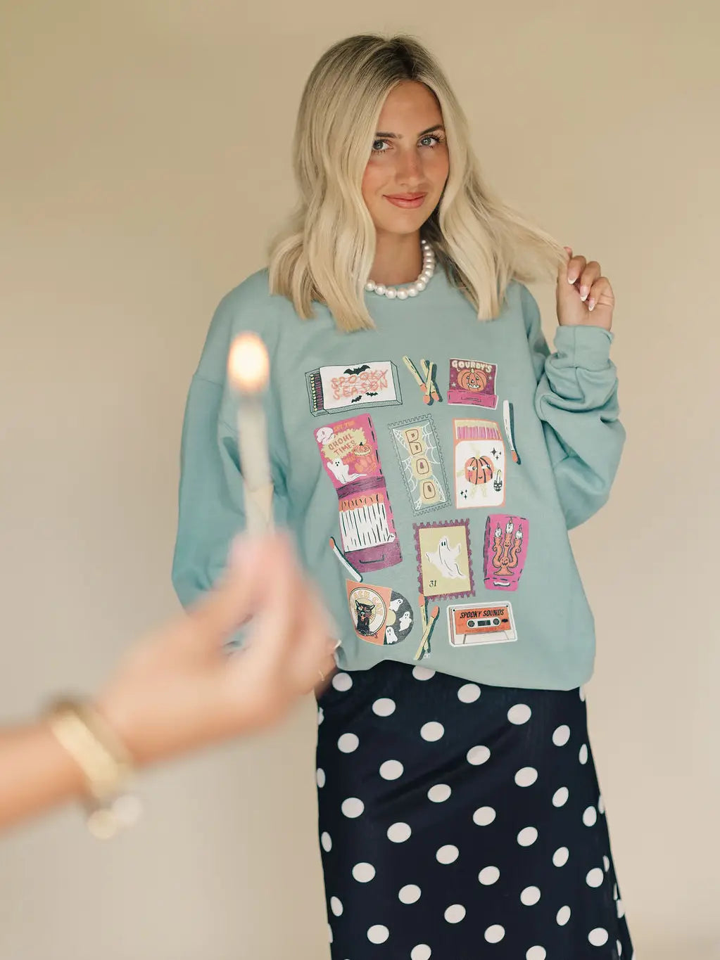 A women's light sage green crewneck pullover sweatshirt featuring vintage-inspired colorful Halloween matchbox illustrations and relaxed drop shoulders.