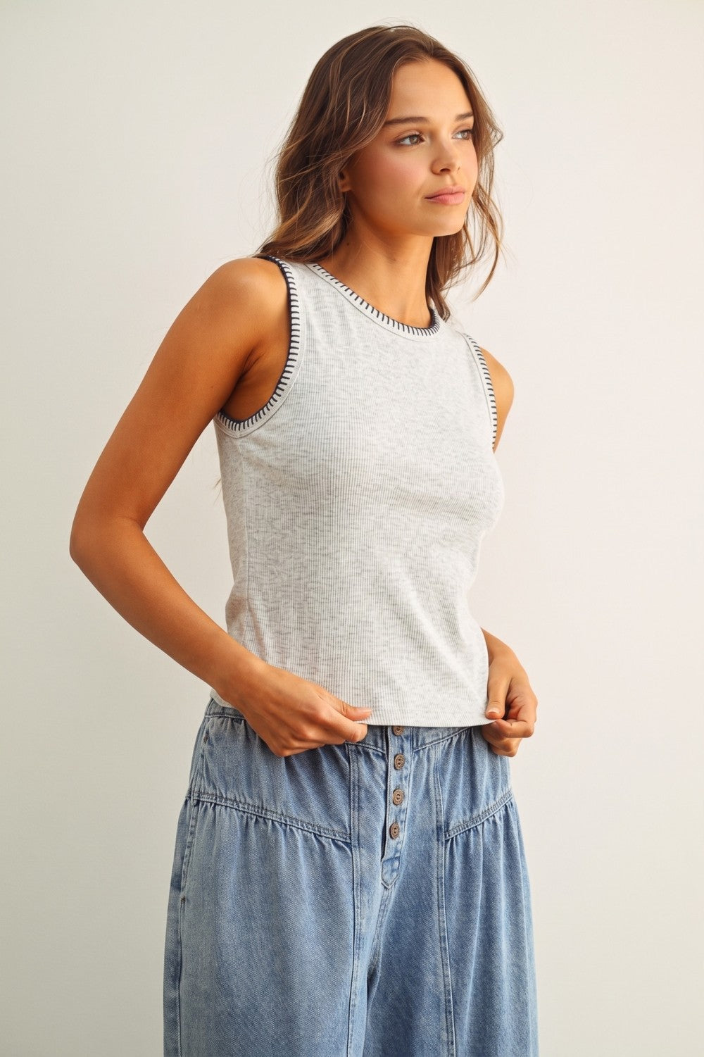 A women's sleeveless crewneck ribbed knit tank top in heather gray featuring a contrasting black blanket-stitch detail along the neckline and armholes.