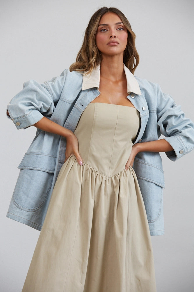 A women's relaxed oversized light wash denim utility jacket featuring a cream-colored pointed contrast collar, a button-front closure, and large front patch pockets with flaps.