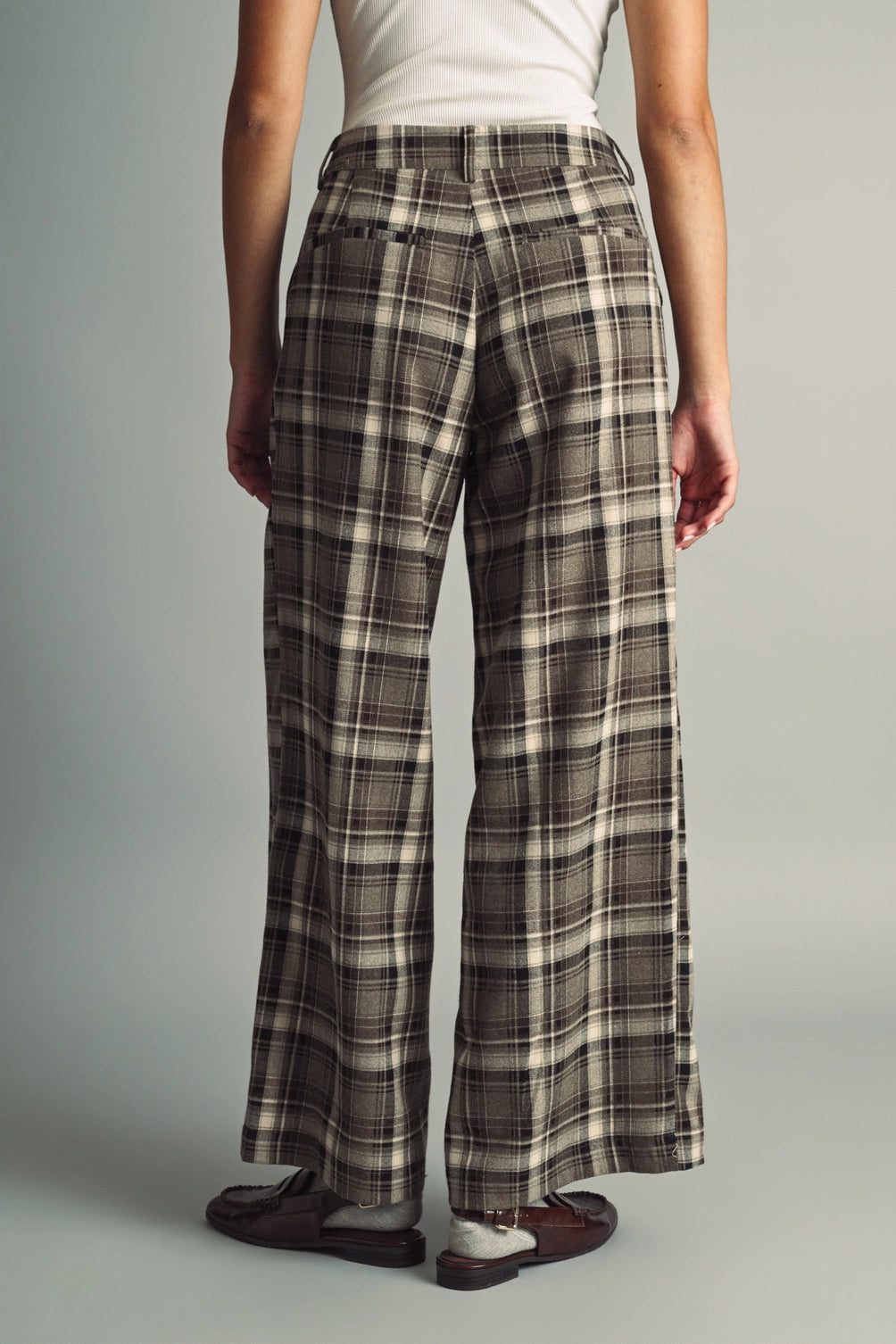 A women's high-waisted wide-leg plaid trousers in black and warm brown featuring front pleats, belt loops, and a relaxed straight drape.