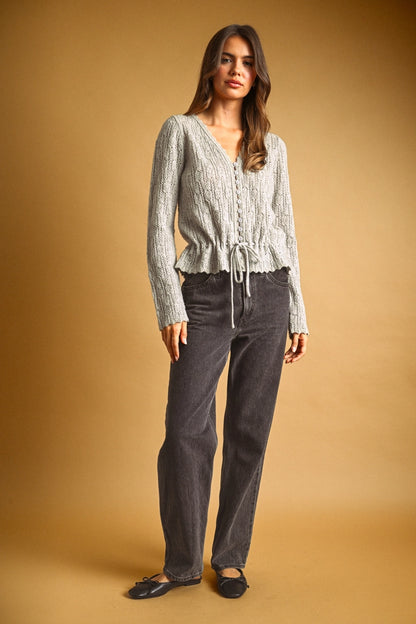A women's light gray long-sleeve textured lace knit cardigan sweater featuring a button-down front, scalloped V-neckline, and an adjustable drawstring tie waistline.