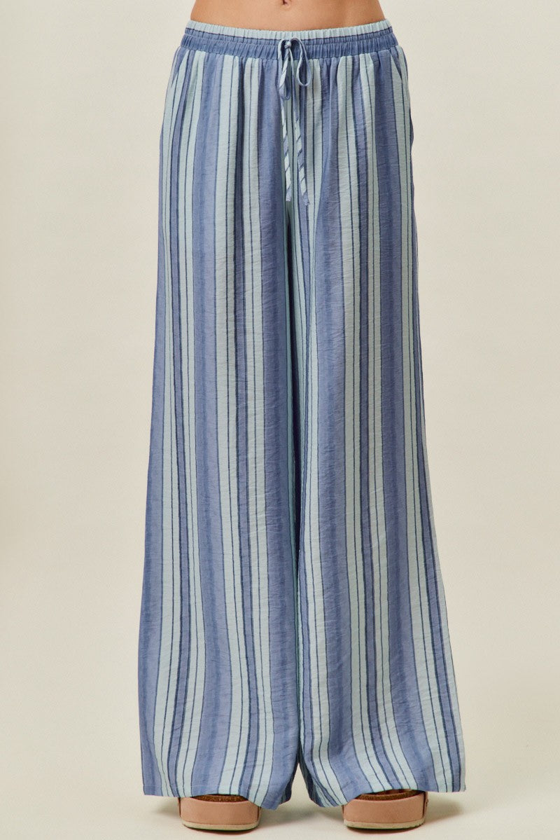 A pair of women's high-waisted wide-leg pull-on pants featuring vertical stripes in shades of blue with a gathered elastic drawstring waistband and side pockets.