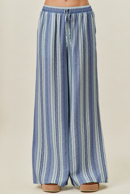 A pair of women's high-waisted wide-leg pull-on pants featuring vertical stripes in shades of blue with a gathered elastic drawstring waistband and side pockets.