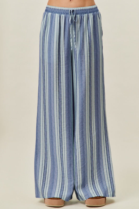 A pair of women's high-waisted wide-leg pull-on pants featuring vertical stripes in shades of blue with a gathered elastic drawstring waistband and side pockets.