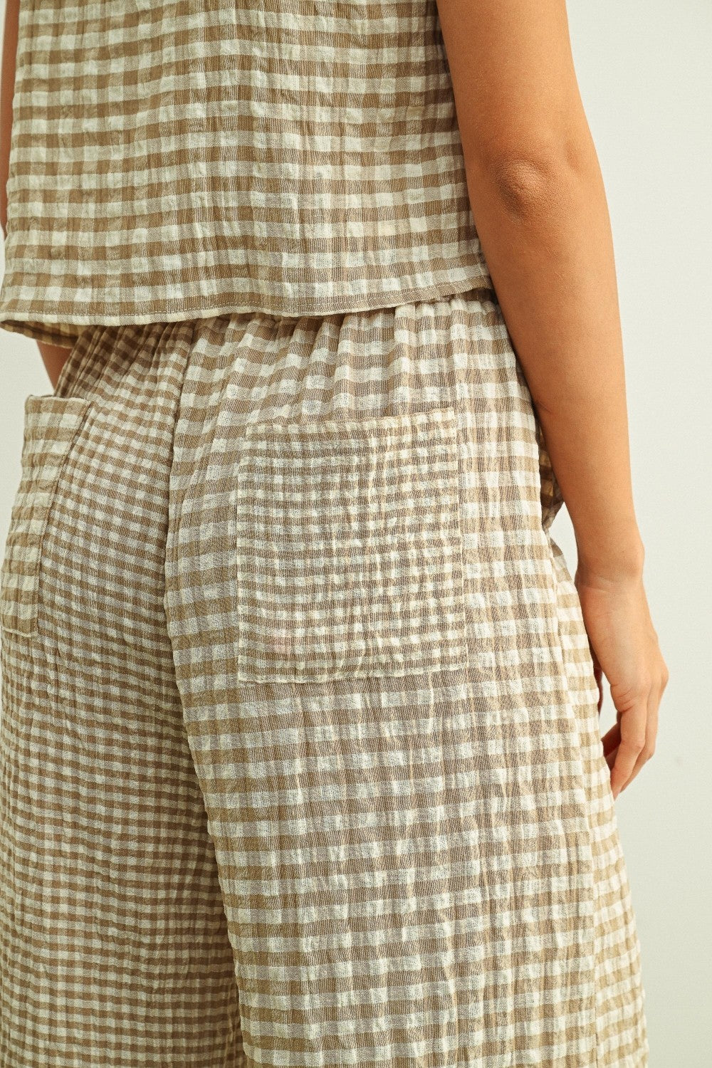 Tan and cream mixed gingham print pants featuring a high-rise elastic drawstring waistband, a relaxed straight-leg silhouette, and a lightweight textured fabric.