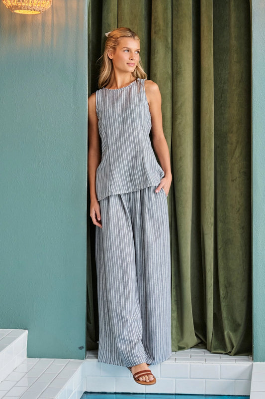 A women's two-piece pinstripe clothing set in a muted gray and white color-way featuring a sleeveless high-neck tunic top and matching high-waisted flowing wide-leg pants with side pockets.