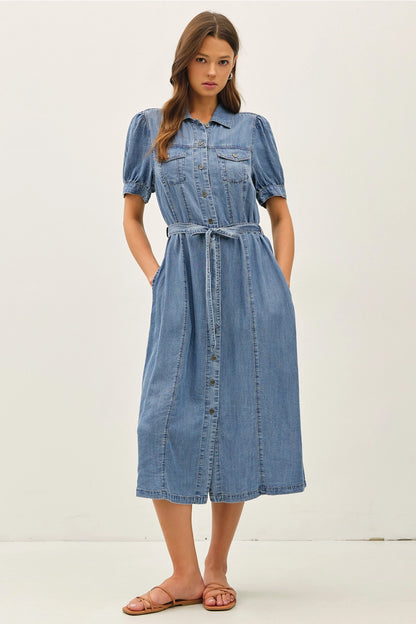 A women's short puff-sleeve denim shirt dress in a light wash featuring a pointed collar, a full button-down front, a matching waist tie belt, and convenient side pockets.