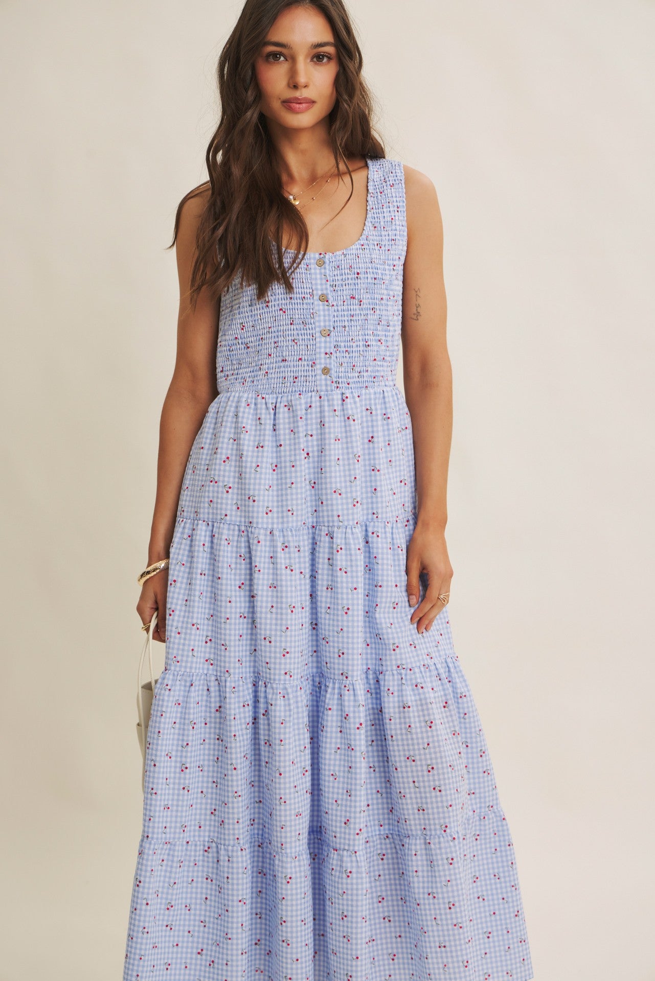 Cherry gingham print maxi dress in the color sky blue. The dress has a smocked bust, round neck, button-down detail, side pockets and comes lined. 