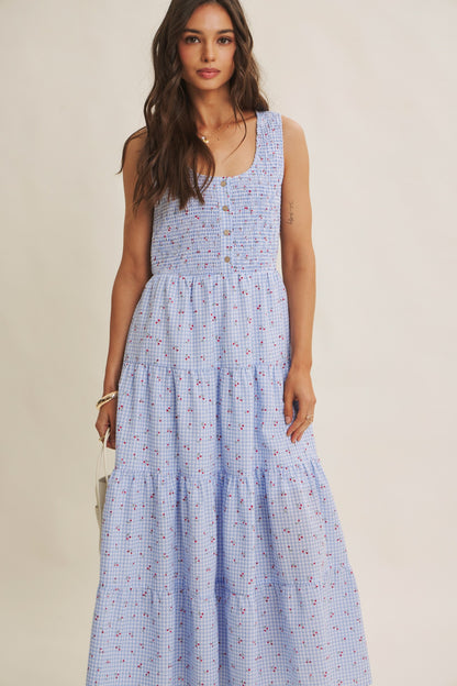 Cherry gingham print maxi dress in the color sky blue. The dress has a smocked bust, round neck, button-down detail, side pockets and comes lined. 