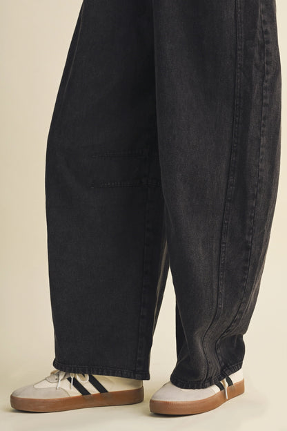 A pair of women's high-waisted wide-leg twill overalls in a vintage washed black denim finish featuring classic adjustable shoulder straps, a front chest pocket, and side pockets.