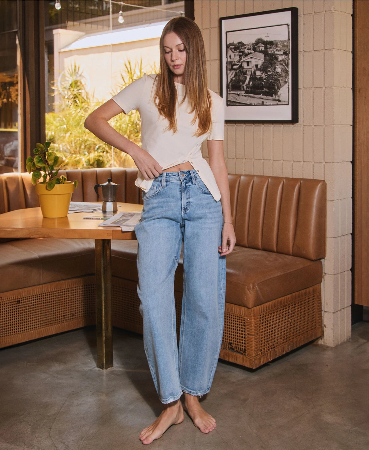 Women's light wash high-rise barrel leg jeans featuring a relaxed curved silhouette, subtle distressing, and an ankle-length hem.