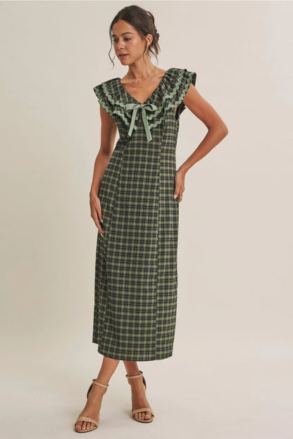 A women's ruffle midi dress featuring an evergreen and navy plaid pattern, a double-ruffle v-neck collar with sage green ric rac trim, a front bow tie, and a side skirt slit.