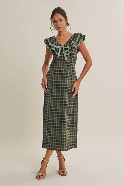 A women's ruffle midi dress featuring an evergreen and navy plaid pattern, a double-ruffle v-neck collar with sage green ric rac trim, a front bow tie, and a side skirt slit.