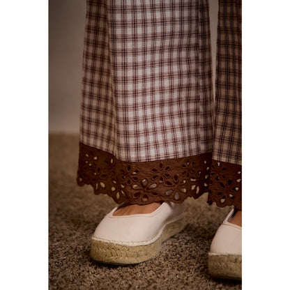 A pair of women's relaxed wide-leg brown and cream plaid pull-on pants featuring an elastic drawstring waist, side pockets, and an embroidered brown eyelet lace scalloped hem.