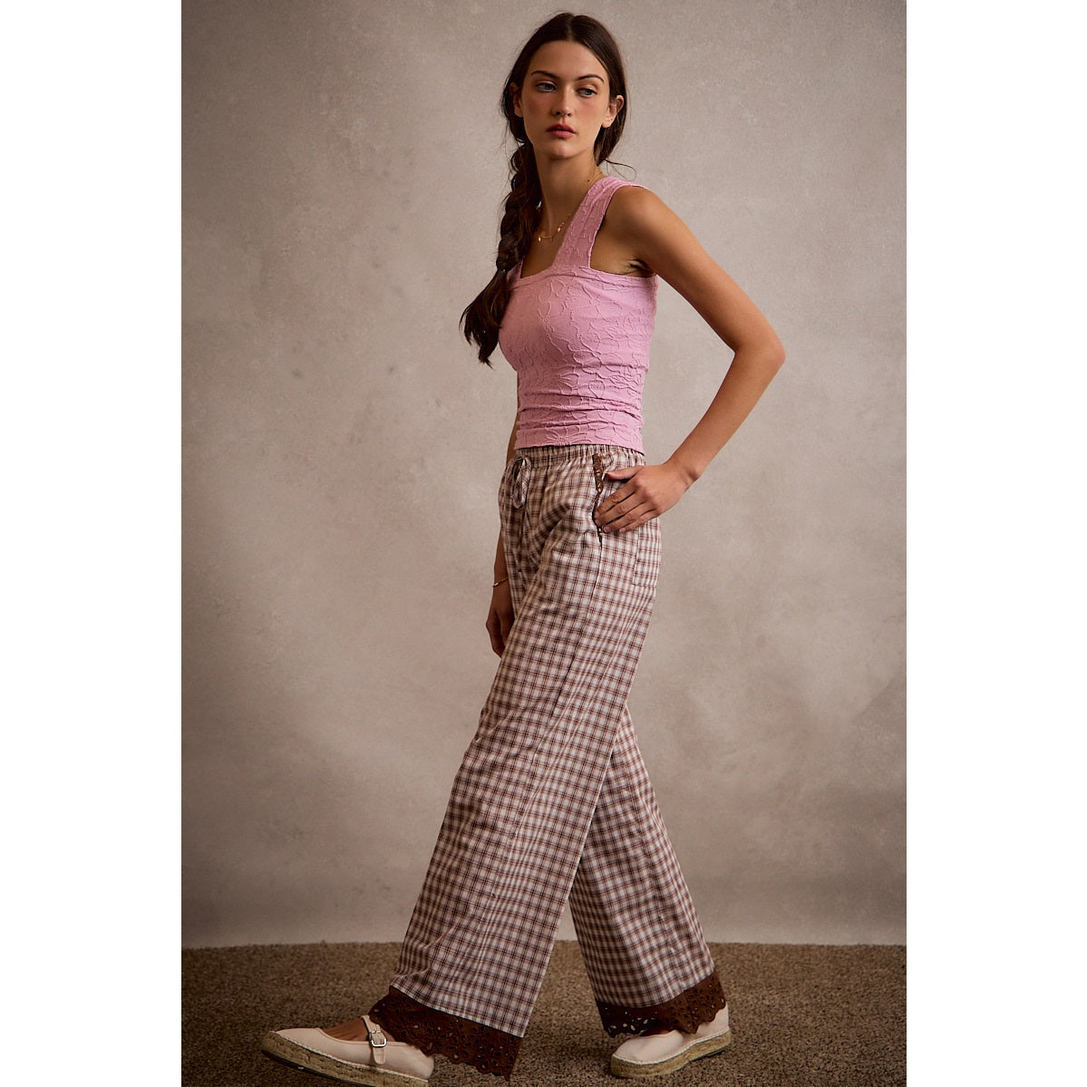 A pair of women's relaxed wide-leg brown and cream plaid pull-on pants featuring an elastic drawstring waist, side pockets, and an embroidered brown eyelet lace scalloped hem.