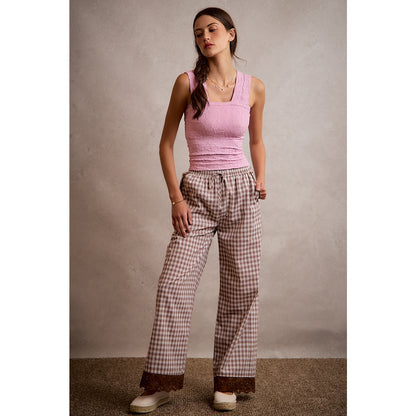 A pair of women's relaxed wide-leg brown and cream plaid pull-on pants featuring an elastic drawstring waist, side pockets, and an embroidered brown eyelet lace scalloped hem.