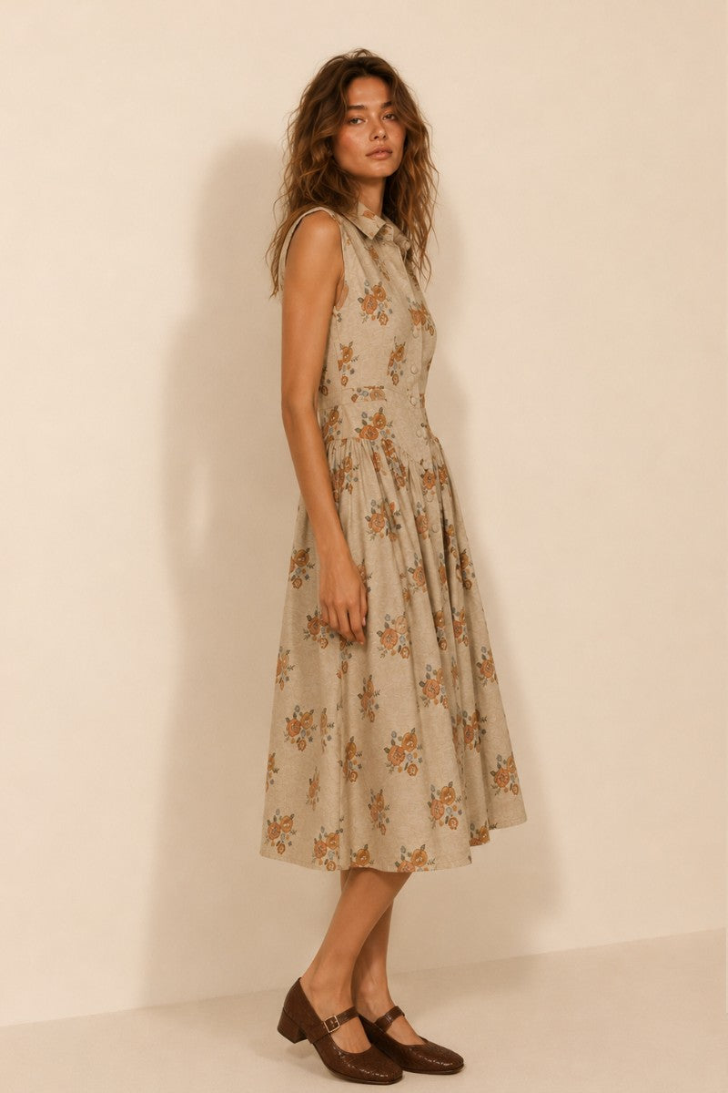A women's sleeveless cream midi dress featuring a warm floral print, a collared neckline, front button closures, a gathered waistline, and functional side pockets.