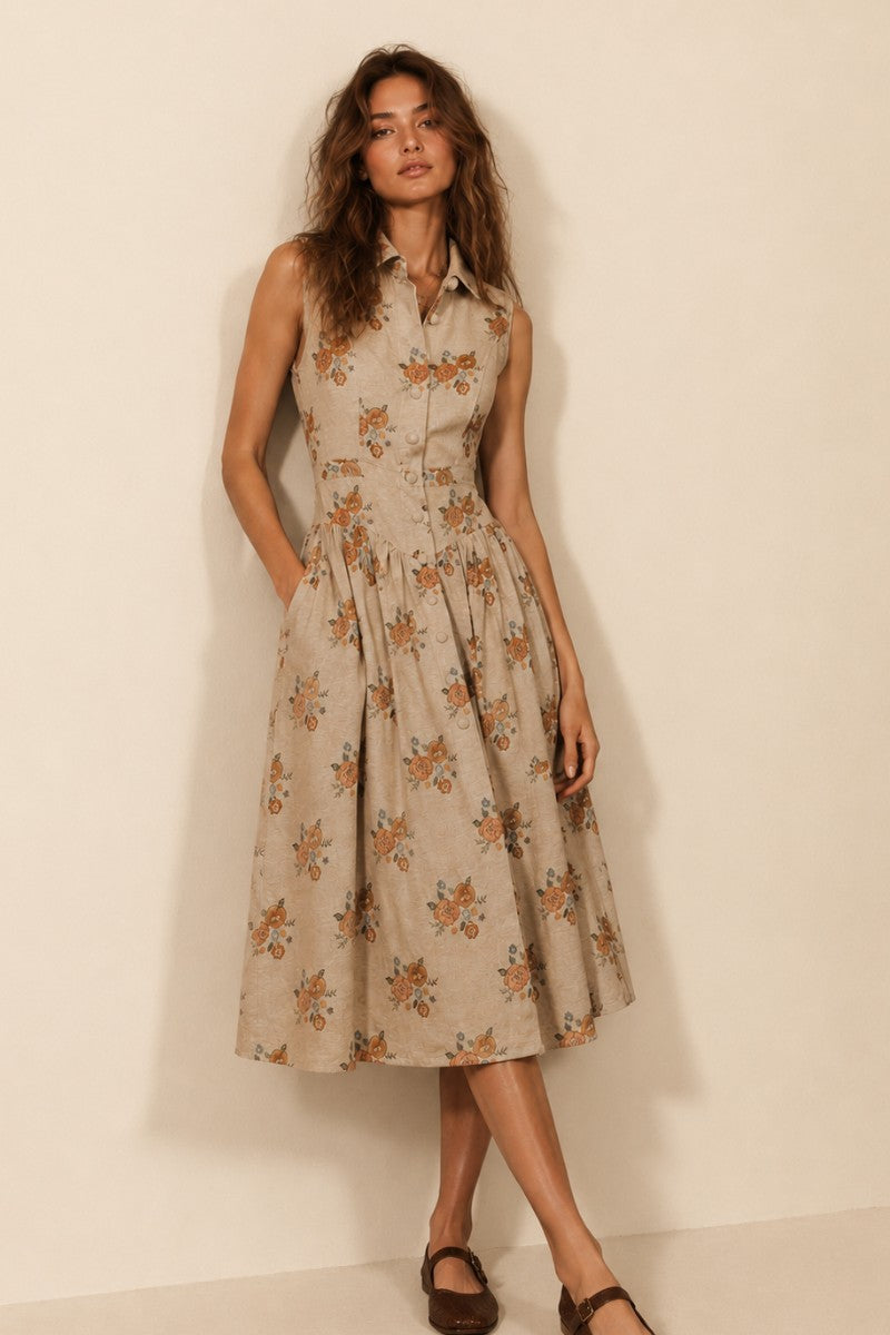 A women's sleeveless cream midi dress featuring a warm floral print, a collared neckline, front button closures, a gathered waistline, and functional side pockets.