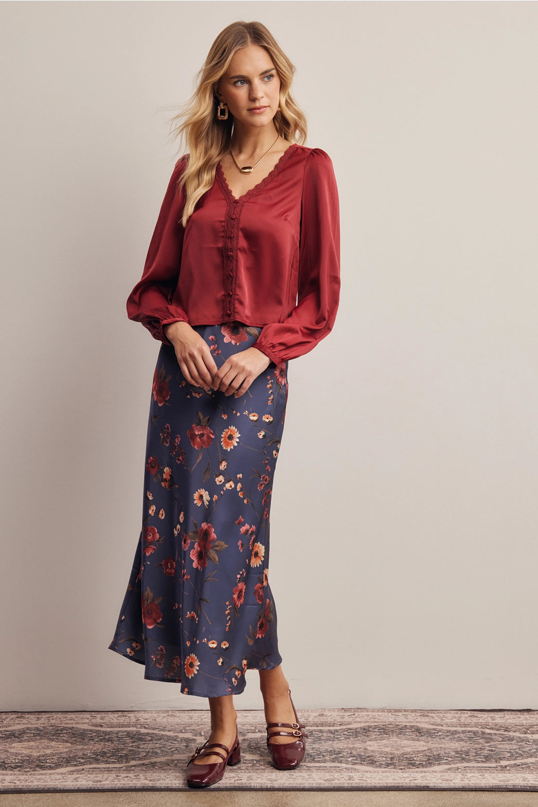 A women's bias-cut satin midi skirt in a midnight navy blue floral print featuring warm rust and amber blossoms with an elasticized waistband.