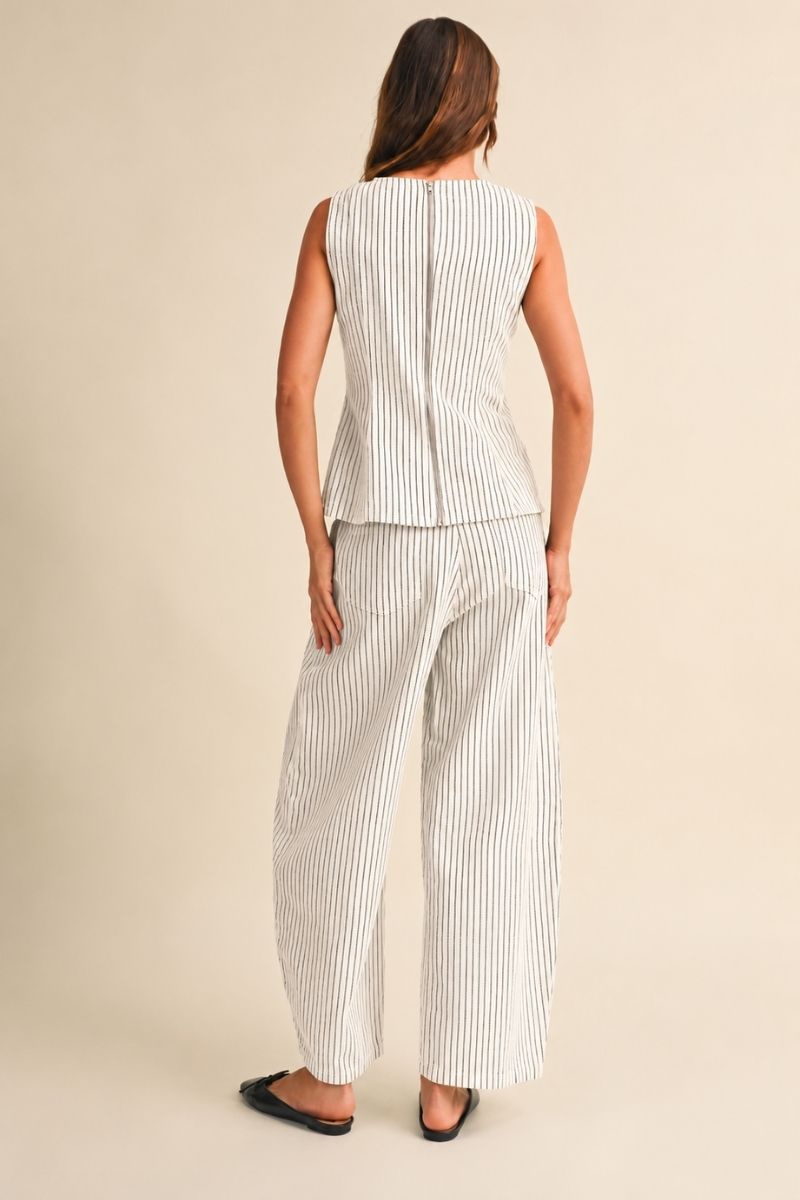 A women's two-piece matching set in a natural oatmeal and black pinstripe pattern featuring a sleeveless round-neck peplum top and relaxed wide barrel-leg pants paired with black flats.