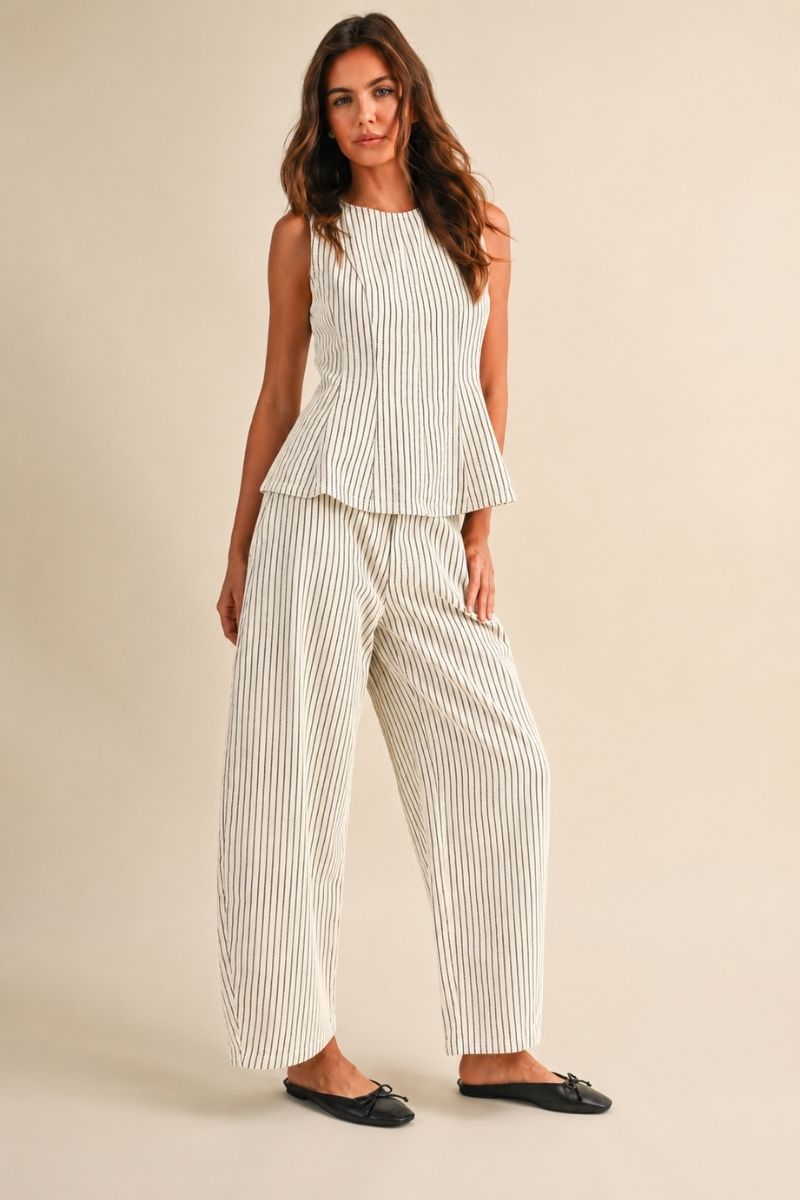 A women's two-piece matching set in a natural oatmeal and black pinstripe pattern featuring a sleeveless round-neck peplum top and relaxed wide barrel-leg pants paired with black flats.