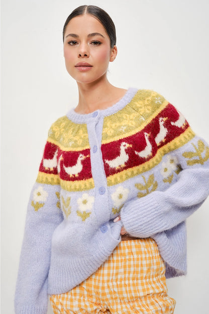 A women's soft lilac brushed knit button-down cardigan featuring a mustard yellow and burgundy Nordic yoke pattern with geese and floral garden motifs.