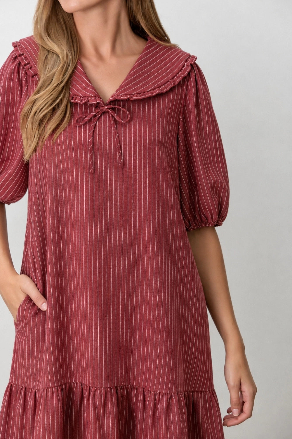 A women's relaxed short-sleeve shift dress in dark red and ivory striped denim featuring an oversized sailor collar with a tie neckline and a ruffled hem.